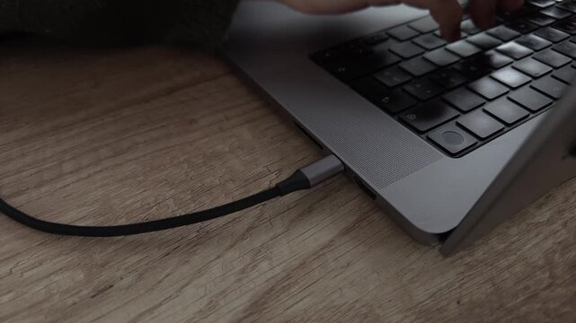Hand connecting USB Type-C cable to laptop followed by typing and disconnecting.