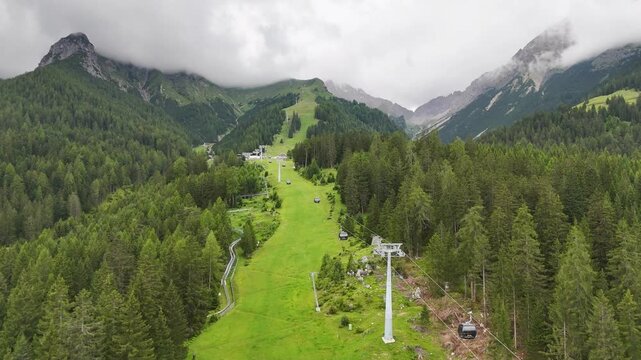 22 july 2024, Imst, Austria. forward drone flight above ski slope in summer, beautiful fresh green meadows, pristine alpine pine forest trees during summer day. Gondola lift, U alm. Hiking trail. Outd