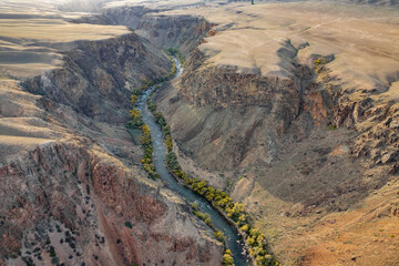 Aerial view of a winding river cutting through a vast arid canyon landscape.