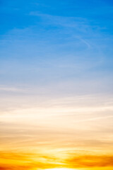 Fototapeta premium Sunset or sunrise sky with a vibrant gradient of orange, gold, and soft blue. Clear atmosphere with wispy clouds. Peaceful, natural light background. hope, freedom, new day Concepts, Vertical