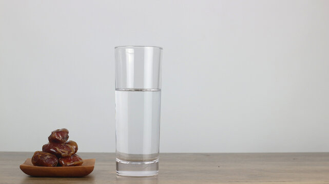 Ramadan iftar concept with dates and fresh water on wooden table. Traditional fasting break, Islamic culture, healthy nutrition, minimal style, clean white background