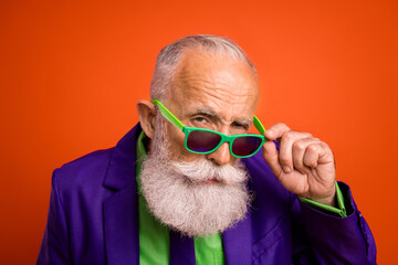 Senior man with bright green sunglass wears purple suit and lime shirt in a bold retro portrait