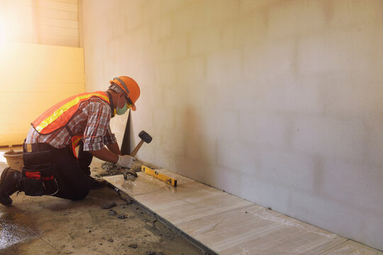 Close-up of a tiler installing ceramic tiles in a new build building