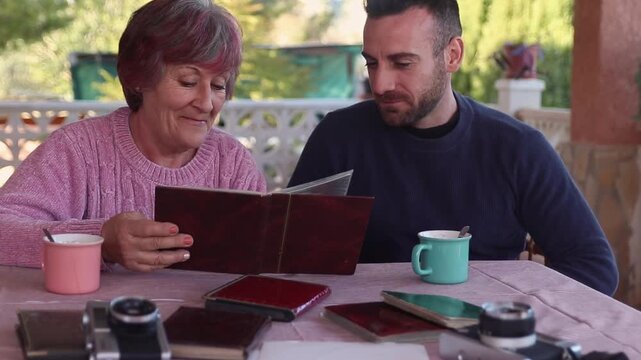 Mother and son looking at a photo album and reliving precious moments. Nostalgia concept