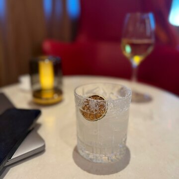 Close-up of a margarita cocktail and glass of wine on a table with a laptop and mobile phone in an airport lounge