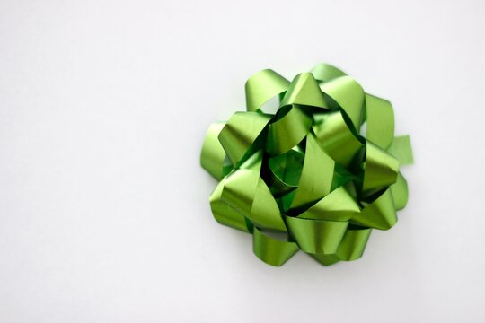 Overhead view of a Single green present bow on a white background