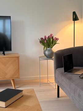 Close-up of an open laptop computer with a blank screen and pair of glasses on a sofa with cushions in a living room