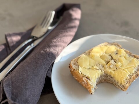 Close-up of half a traditional Danish buttered bread roll with a missing bite showing tooth marks (tandsmor) on a plate