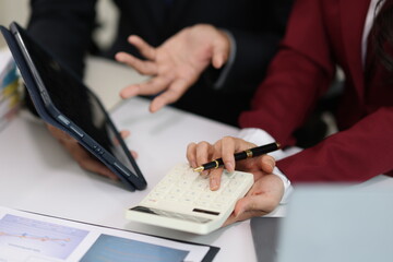 Business colleagues discussing financial data and using calculator and tablet during a meeting, analyzing charts and graphs, planning strategy and making business decisions.