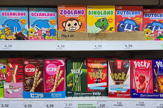 Penang, Malaysia: Nov 06, 2025: A colorful display of snack boxes including Meiji Oceanland, Zooland, and Dinoland biscuits alongside various Glica Pocky and YBC Picola flavors in a grocery store.