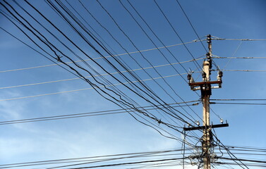 Strommast mit Leitungen vor strahlend blauem Himmel