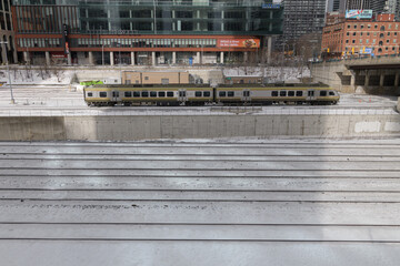 Naklejka premium Union Pearson Express zooming by on the Union Station Rail Corridor with view of The Well complex, viewed from Iceboat Terrace, Toronto
