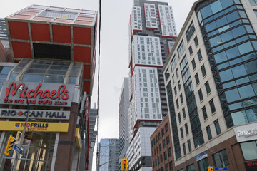 Naklejka premium Michael's and No Frills signs at Rio Can Hall incl (tall building at right) Picasso Condominiums, looking west on Richmond St W at John St, Toronto