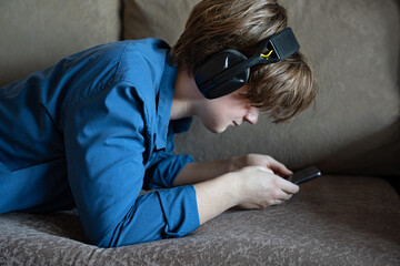 Young man with smartphone and headphones lying on sofa