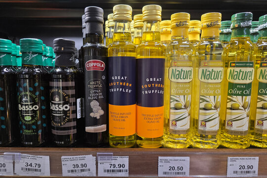 Penang, Malaysia: Nov 06, 2025: A selection of specialty cooking oils including Coppola white truffle oil, Great Southern Truffles infused oil and Naturel extra light olive oil on a supermarket shelf.