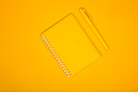 Yellow pen and notebook on a yellow background