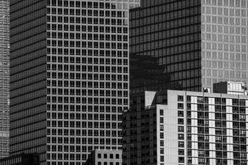 Black and white abstract urban background featuring a dense cluster of modern skyscraper facades...