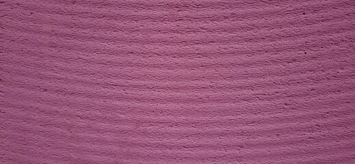 Fototapeta premium A pinkish-purple hue dresses this surface streaked with horizontal lines, like a visual breath. This wall becomes an abstract canvas, blending softness and structure, perfect for creative projects.