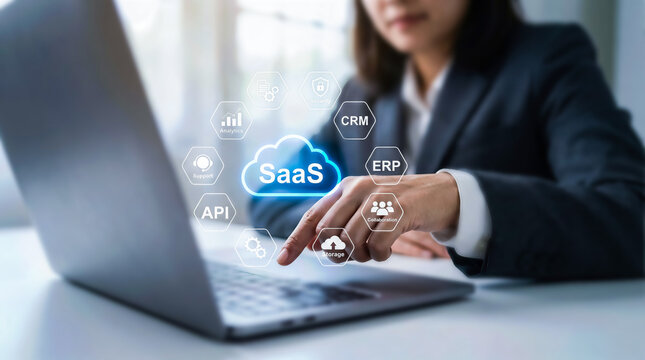 Businesswoman interacting with a laptop displaying a holographic interface with saas cloud computing icons and digital business technology concepts in a modern office setting