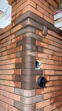 Building a heating stove. Made of multicolored bricks. Shows a chimney with a flue spreader. A convection heating pipe and a stove bench. Vertical video.
