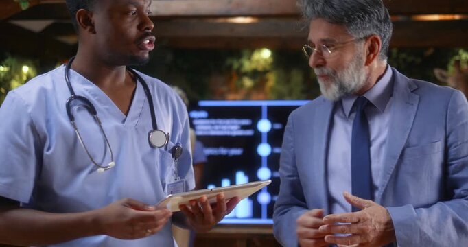 Doctor presenting medical project to senior business executive during professional meeting, followed by handshake symbolizing healthcare partnership, investment agreement, or strategic collaboration.