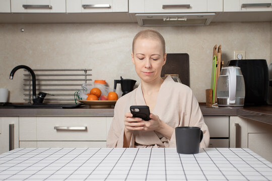 young woman with short regrown hair after chemotherapy sits in a cozy kitchen,