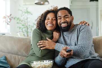 Portrait of a happy young couple watching tv together at home. Shot of a couple resting on the...