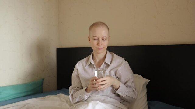 Oncology patient in bed drinking water, bald woman in remission focusing on hydration and self-care, concept of home recovery, medical treatment side effects relief and supportive healthcare