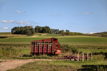 Fototapeta premium Rolling Green Farmland with Vintage Farm Equipment