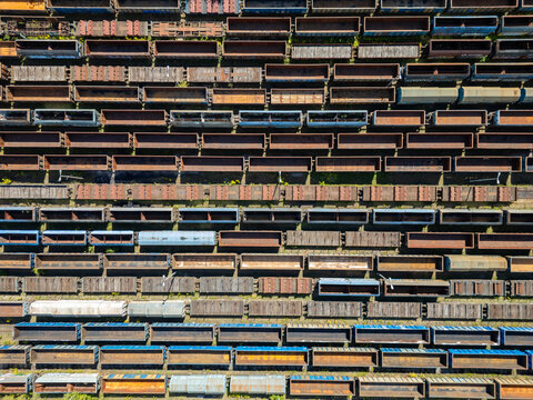 Many railroad cars (rail cars) of different cargo types on multiple parallel railway tracks, seen from above the railway station