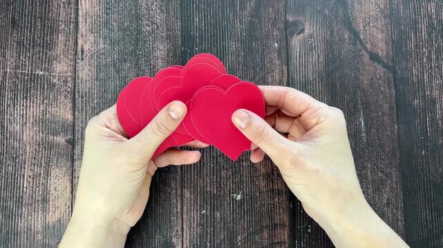 Two hands sorting through red paper Valentine hearts.