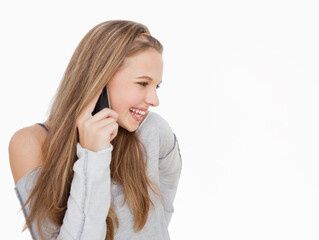 Fototapeta premium Teenage female holding smartphone to right ear smiling in studio off-shoulder sweater and headband