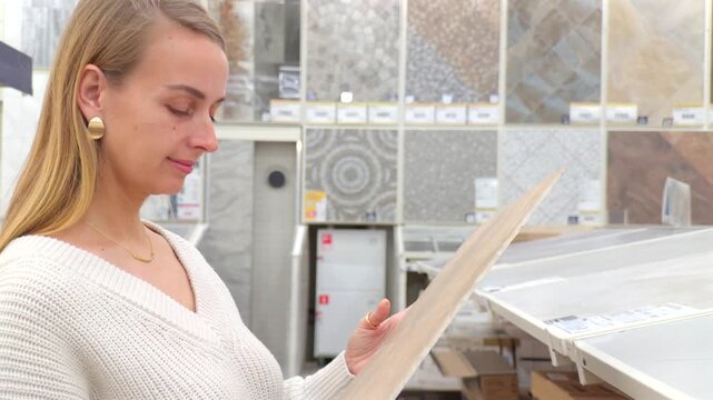 Woman examining tile sample while choosing materials in home improvement store