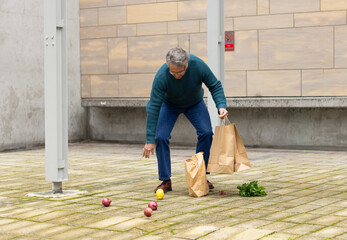 Paper shopping bags are lying open on paved courtyard with scattered apples and lemon © wavebreak3