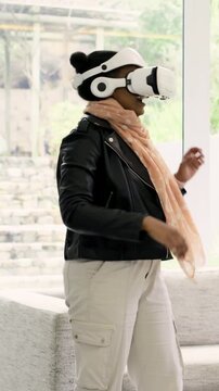 Vertical video: Fixing scarf woman in leather jacket adjusting VR headset, exploring at home