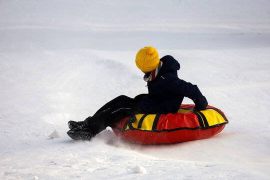 Child having fun on snow tube. Kid is riding a tubing, winter entertainment