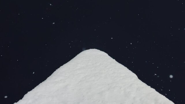 Snow falling on awning night, slow delicate flakes drift and settle into soft mound on house canopy, closeup view reveals powdery texture against deep dark sky, tranquil winter atmosphere