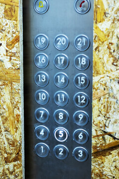 Close examination of scratched metal elevator buttons amid dusty renovation environment