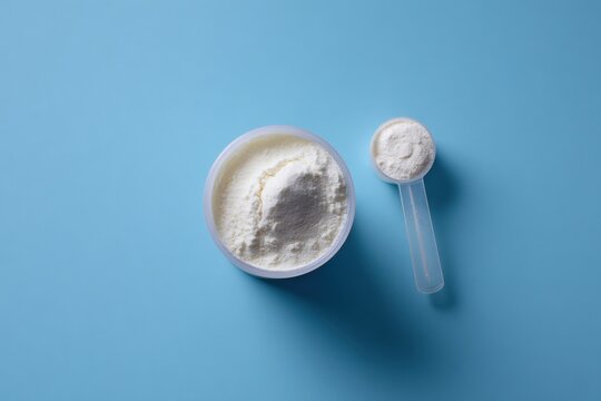 Powdered nutrition: measuring scoop and bowl of white protein against blue background