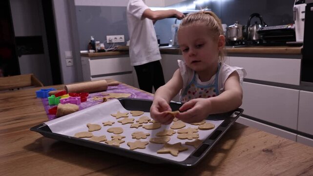 Little child cutting gingerbread dough with star and triangle cookie cutters at home