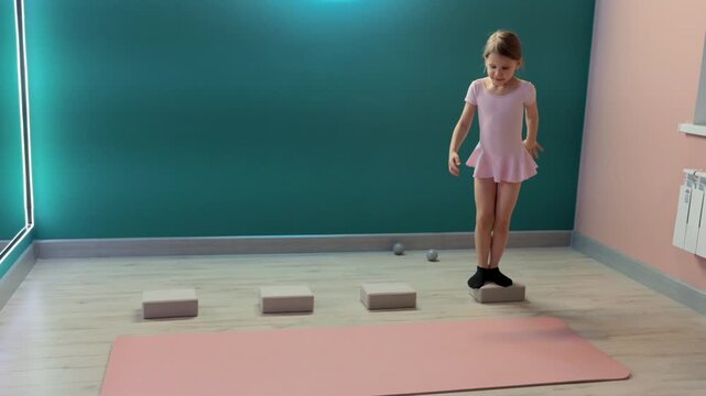 Young girl is practicing balance and coordination by stepping across foam blocks in fitness studio, training footwork and stability