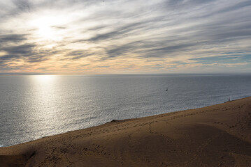 Fototapeta premium Sunset Over Calm Ocean From Dunes With Sailboat On The Horizon
