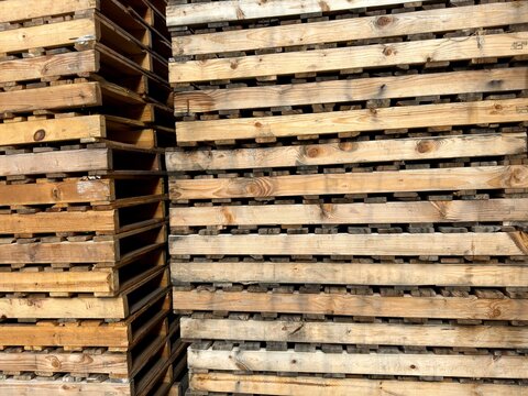 Stacked Industrial Pallets: High stack of wooden shipping pallets showing natural wood grain and industrial texture.