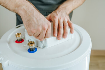 Technician's hands using a screwdriver to repair an electric water heater