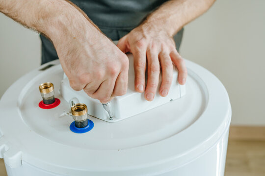 Technician's hands using a screwdriver to repair an electric water heater