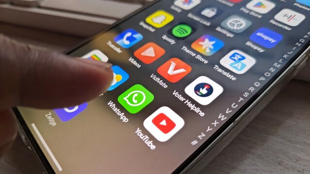Finger pressing on smartphone screen with various app icons