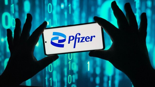 Hands holding smartphone displaying pfizer logo against binary code