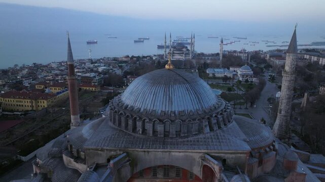 Aerial drone footage of Hagia Sophia (Ayasofya) in Istanbul, Turkey, captured at dusk. The iconic monument features its massive central dome, historic buttresses, and surrounding minarets, standing at
