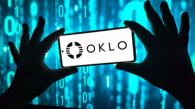 Hands hold smartphone displaying oklo logo against binary code
