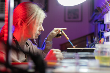 Woman artisan heating metal object with torch in workshop